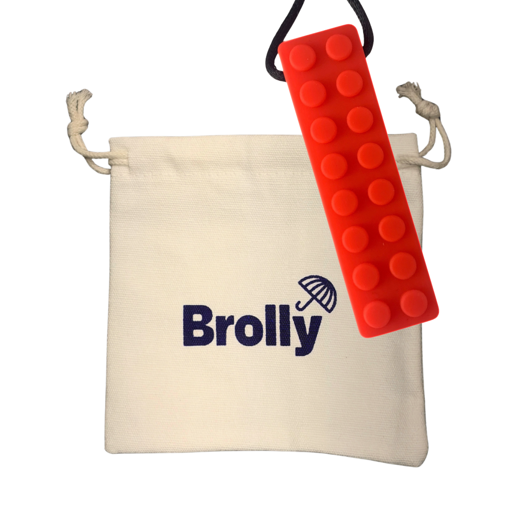 Beige drawstring pouch and brick-shaped Brolly Chew Necklace on a black cord against a white background - Red