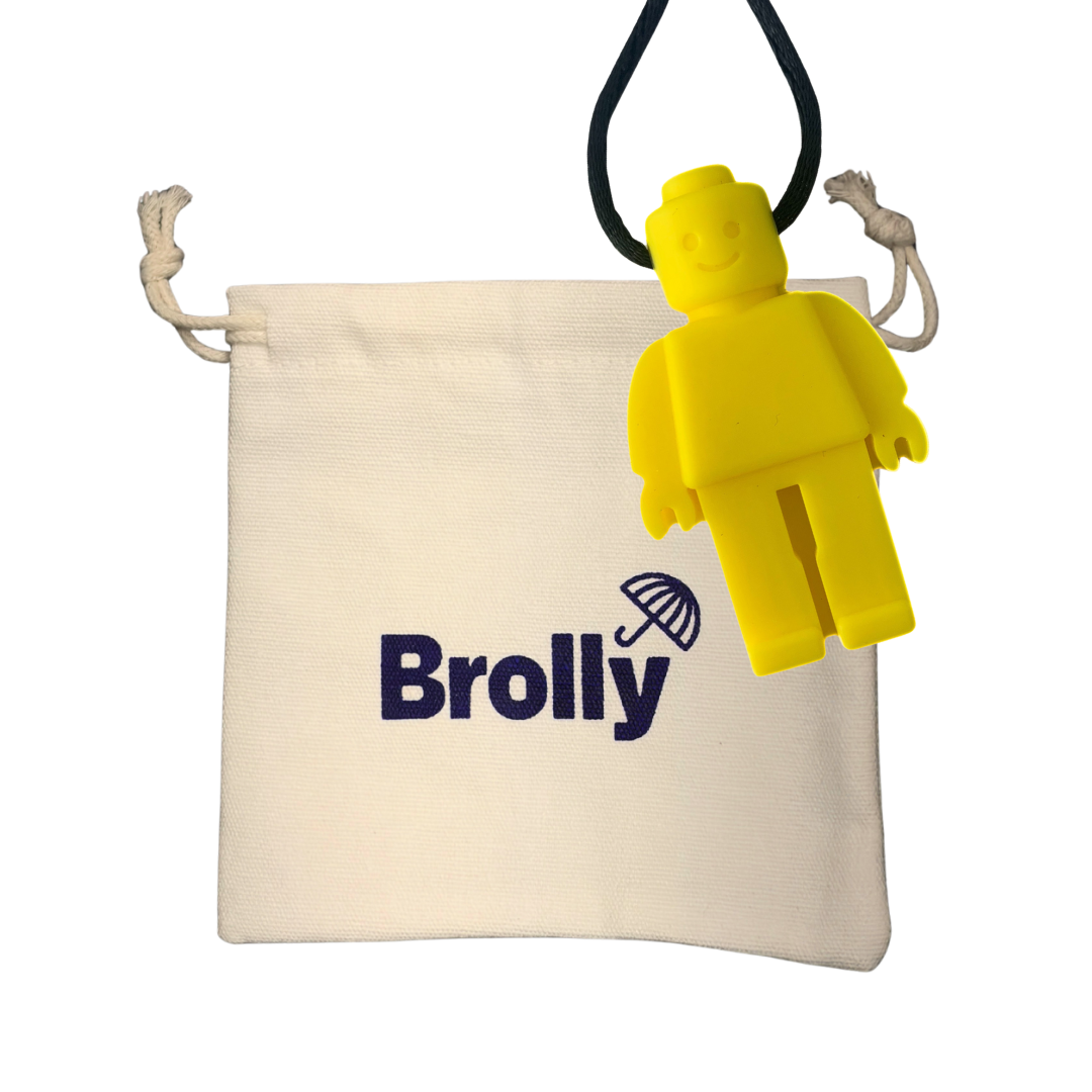 Beige drawstring pouch and Robot-shaped Brolly Chew Necklace on a black cord against a white background - Yellow