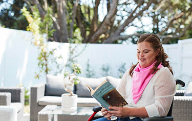Disability women wearing pink adult bib reading outdoor