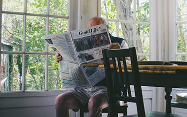 Elderly man reading newspaper in the house
