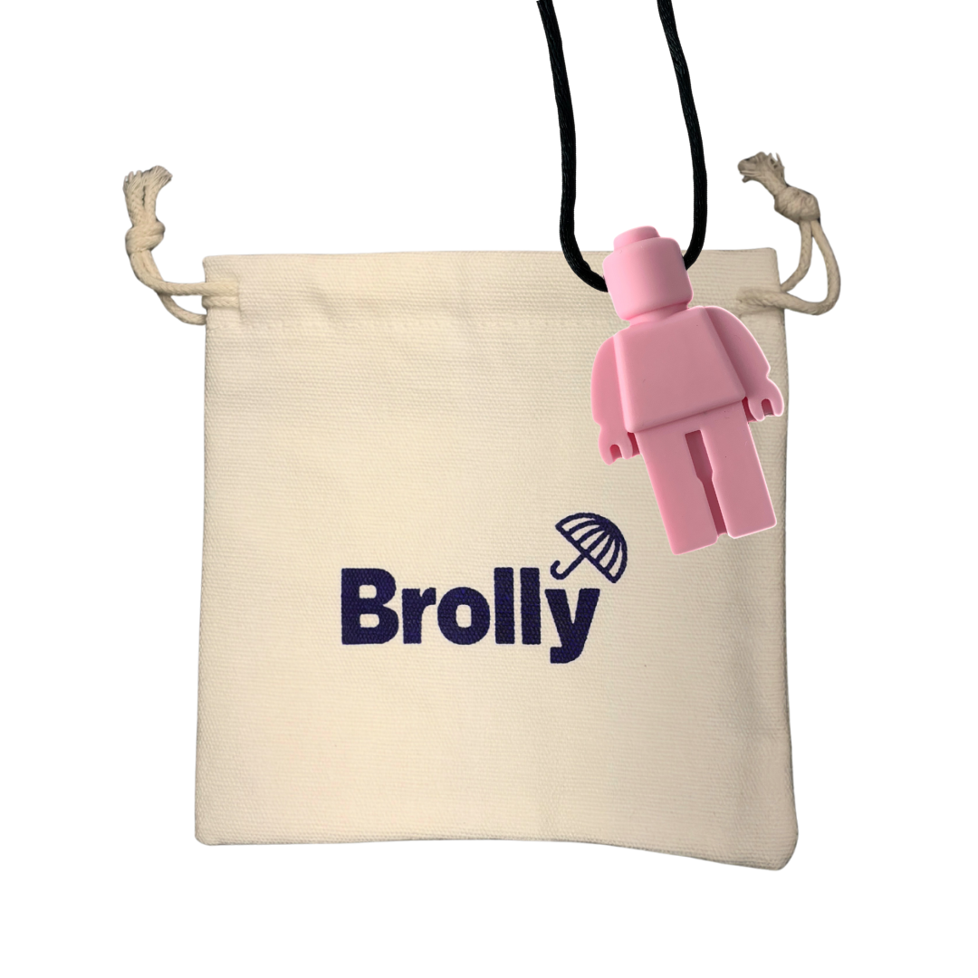 Beige drawstring pouch and Robot-shaped Brolly Chew Necklace on a black cord against a white background - Soft Pink